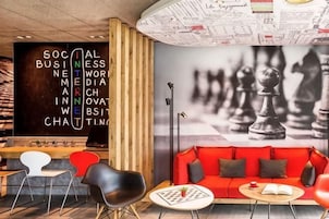 A modern interior with a chessboard mural, a red sofa, and a wooden bookshelf.