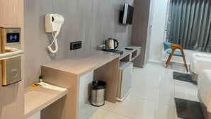 A modern hotel room with a wooden desk, a phone, a kettle, a TV, and a bed. - Hotel Bluzill (Vadodara)