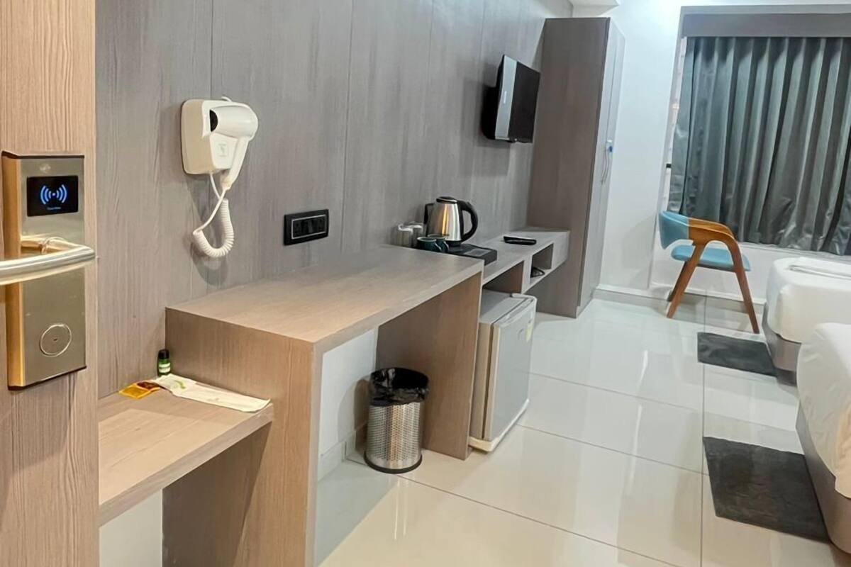 Une chambre d’hôtel moderne équipée d’un bureau en bois, d’un téléphone, d’une bouilloire, d’une télévision et d’un lit.