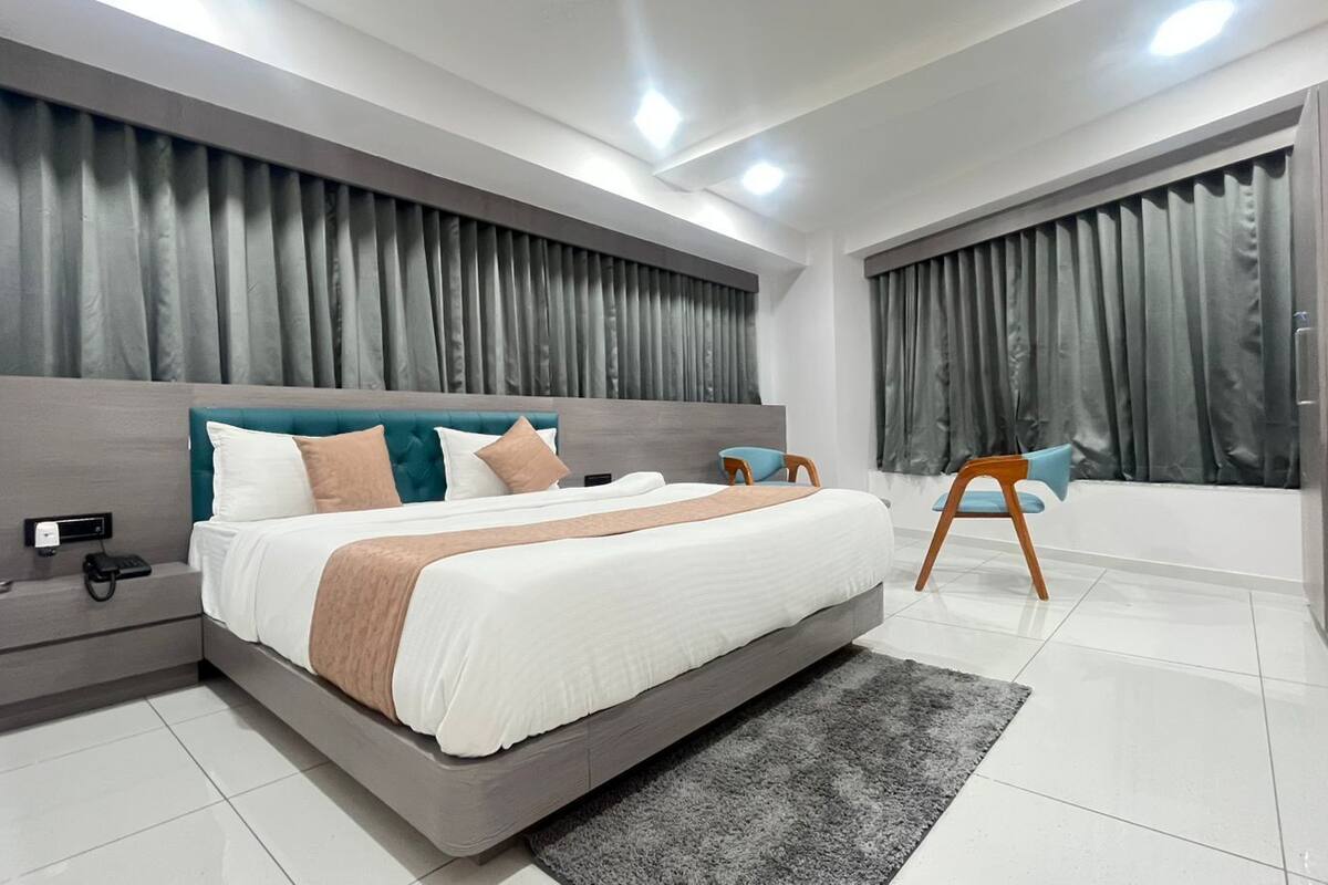 Une chambre moderne avec un grand lit, des tables de chevet, un fauteuil et une salle de bain avec une baignoire.