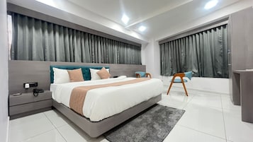 Un dormitorio moderno con una cama grande, mesitas de noche, una silla y un baño con bañera.