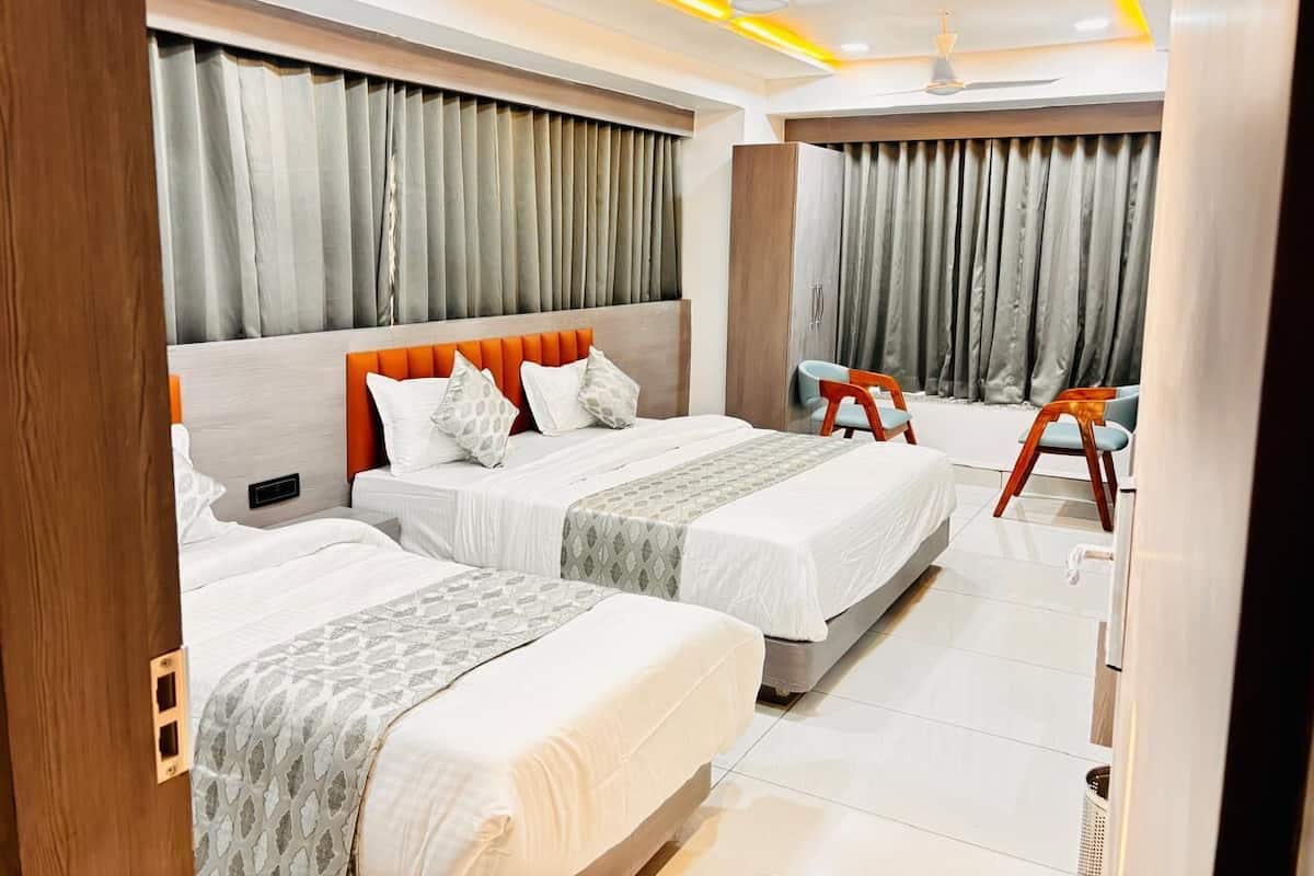 Une chambre d’hôtel avec trois lits, un bureau et une chaise.