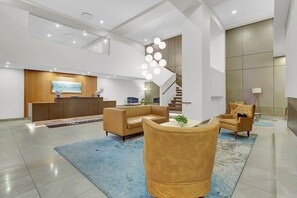 A modern lobby with a reception desk, sofas, a staircase, and a decorative light fixture. - Downtown Cleveland 2 BR 2Bath Rooftop Walking Distance To Stadium, East 4th Str. (Cleveland)