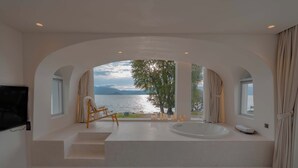 Un baño moderno con bañera, una silla de madera y vistas a un lago.