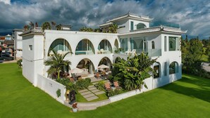 Eine moderne Villa im traditionellen Baustil, mit mehreren Bögen und einem geräumigen Innenhof mit Außenmöbeln.