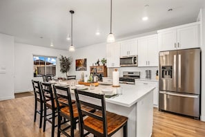A modern kitchen with white cabinets, stainless steel appliances, and a central island with seating. - Skyline 1686, Hot Tub, Garage Game Room, Wii, Community Amenities (Washington)