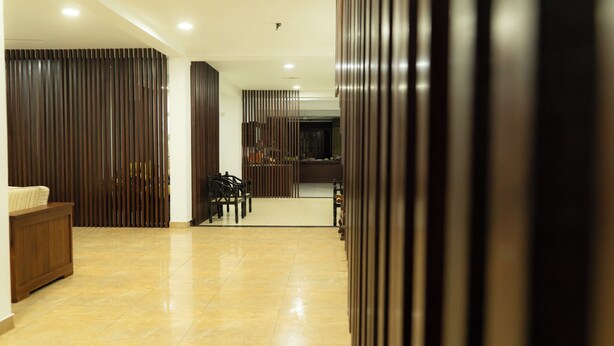 Um lobby moderno de hotel com piso de azulejos brilhante, painéis de madeira e um balcão de recepção.