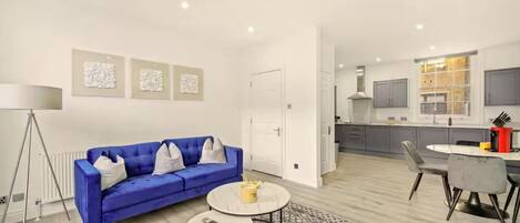 A modern living room with a blue sofa, a coffee table, and a patterned rug.