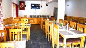 A restaurant with wooden tables and chairs, a tiled floor, and a television mounted on the wall. - The Snowpeak Hunder (Hunder)