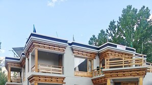 A two-story building with a traditional architectural style, featuring wooden balconies and a car parked in front. - The Snowpeak Hunder (Hunder)