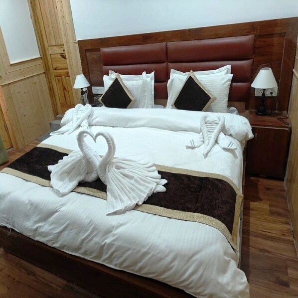 A hotel room with a large bed, wooden headboard, white linens, and decorative swan pillows. - The Snowpeak Hunder (Hunder)