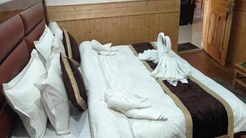 Una habitación de hotel con cabecera de madera, cama con ropa blanca y un detalle en marrón, y un armario de madera.