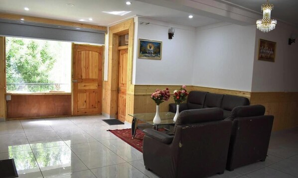 A reception area with a wooden door, a glass table with vases, and a sofa. - The Snowpeak Hunder (Hunder)