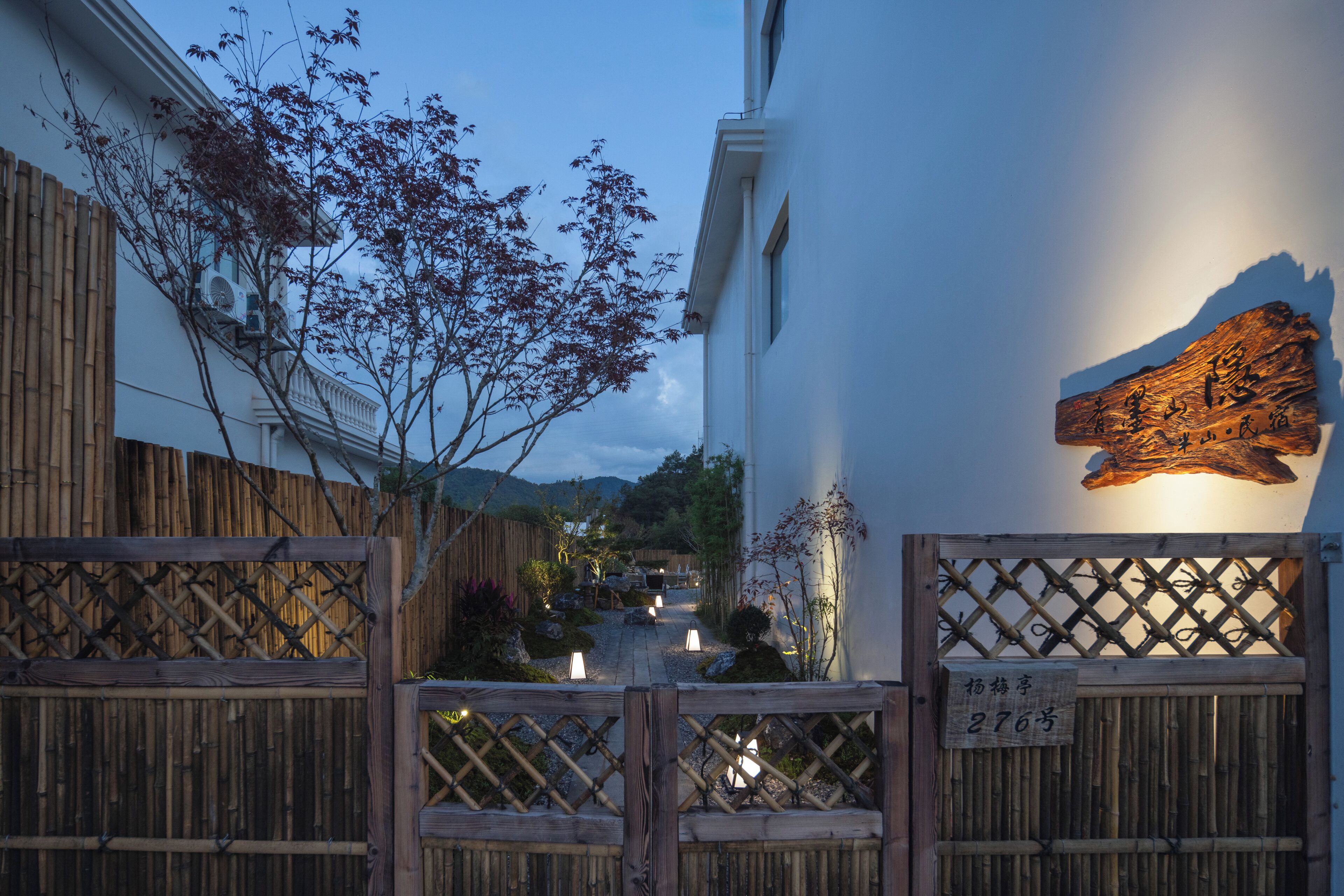 A traditional Japanese building with a wooden gate, a sign with numbers, and a bamboo fence.