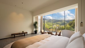 A spacious bedroom with a large bed, a bench, and a table with chairs. - Qingmo Hidden Mid-Mountain Hotel (Jingdezhen)