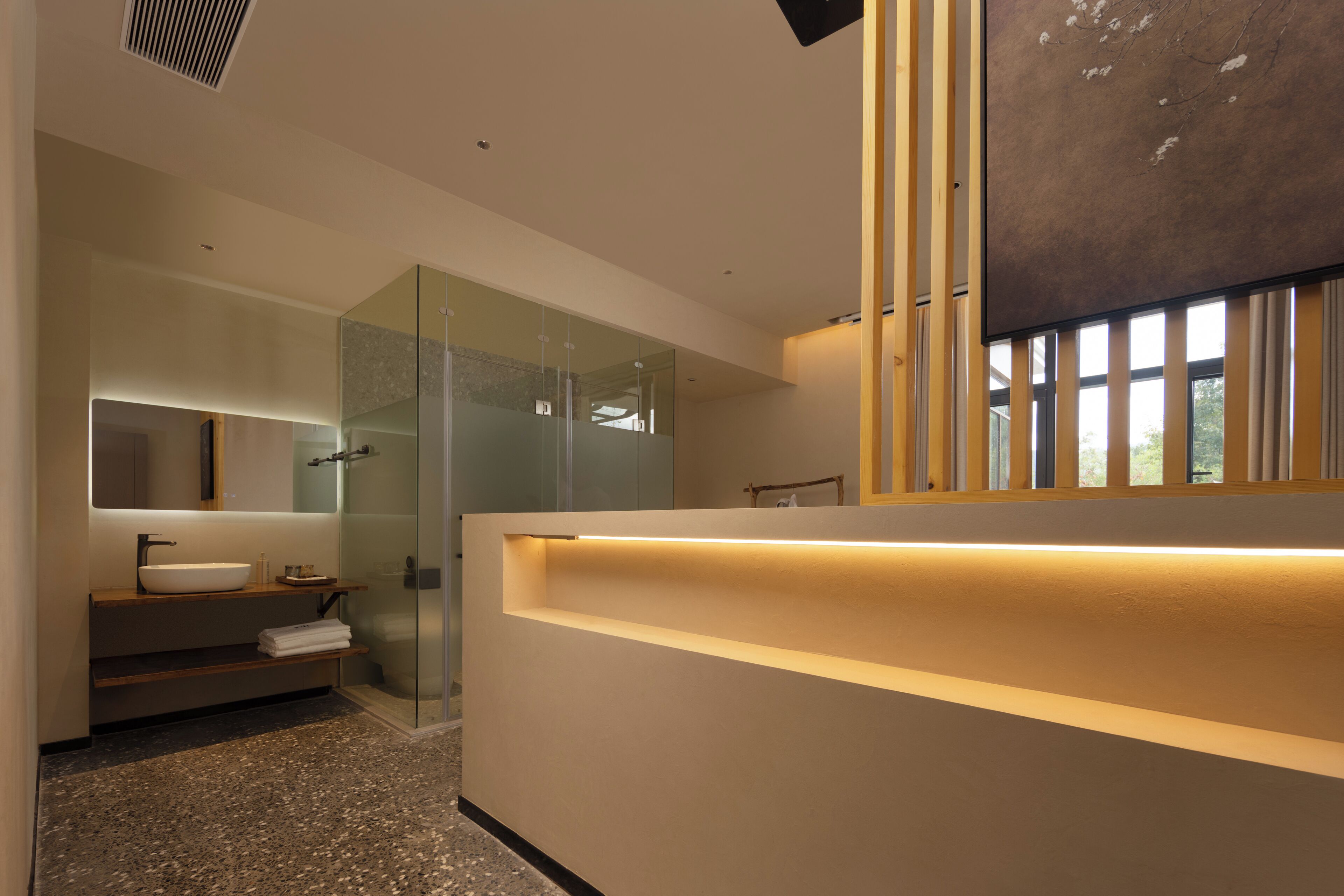Un baño moderno con cabina de ducha de vidrio, tocador con lavamanos y un espejo grande.