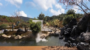 A serene outdoor setting with a wooden deck, a small pond, rocks, and a waterfall. - Qingmo Hidden Mid-Mountain Hotel (Jingdezhen)