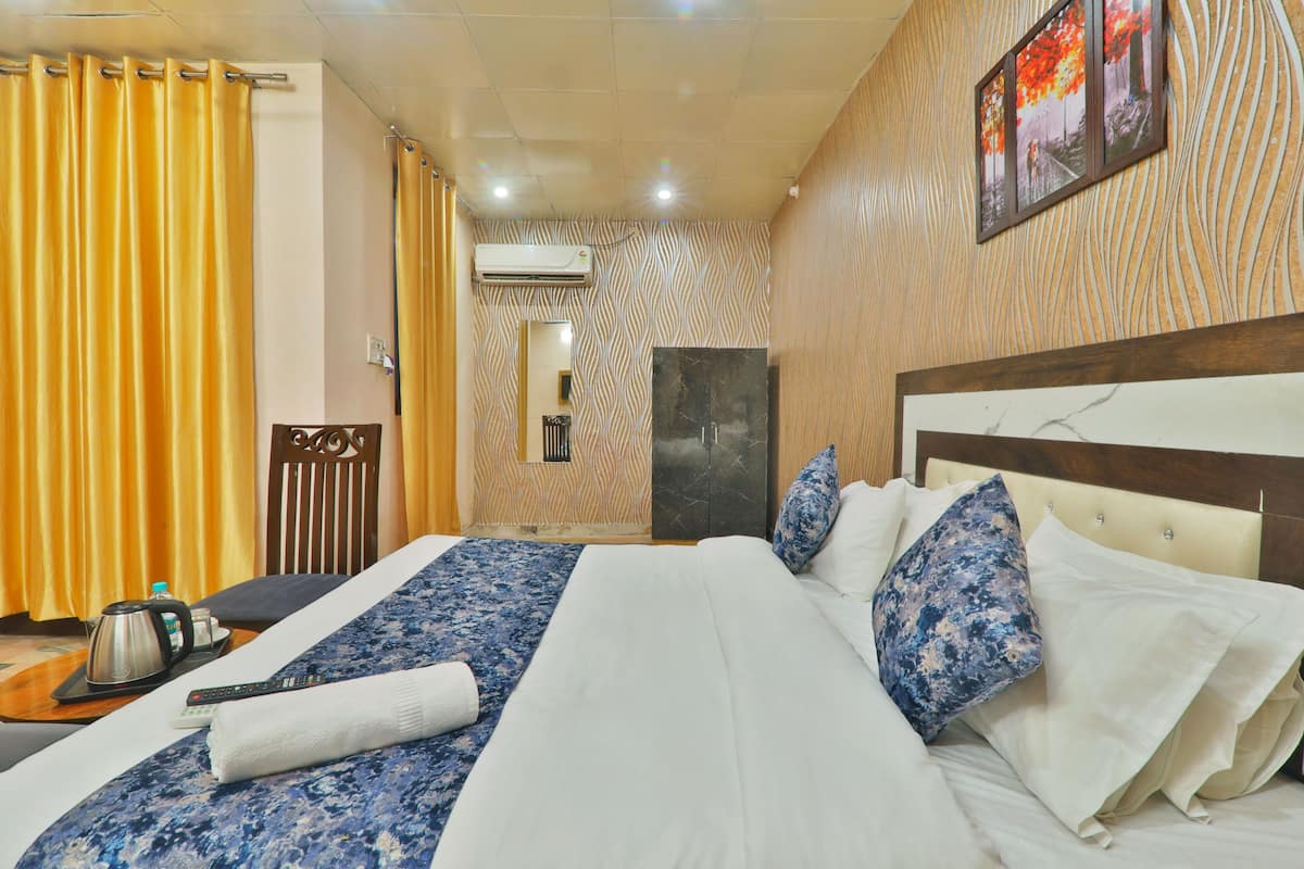 Habitación de hotel con una cama grande, cabecera de madera, televisor de pantalla plana y armario.