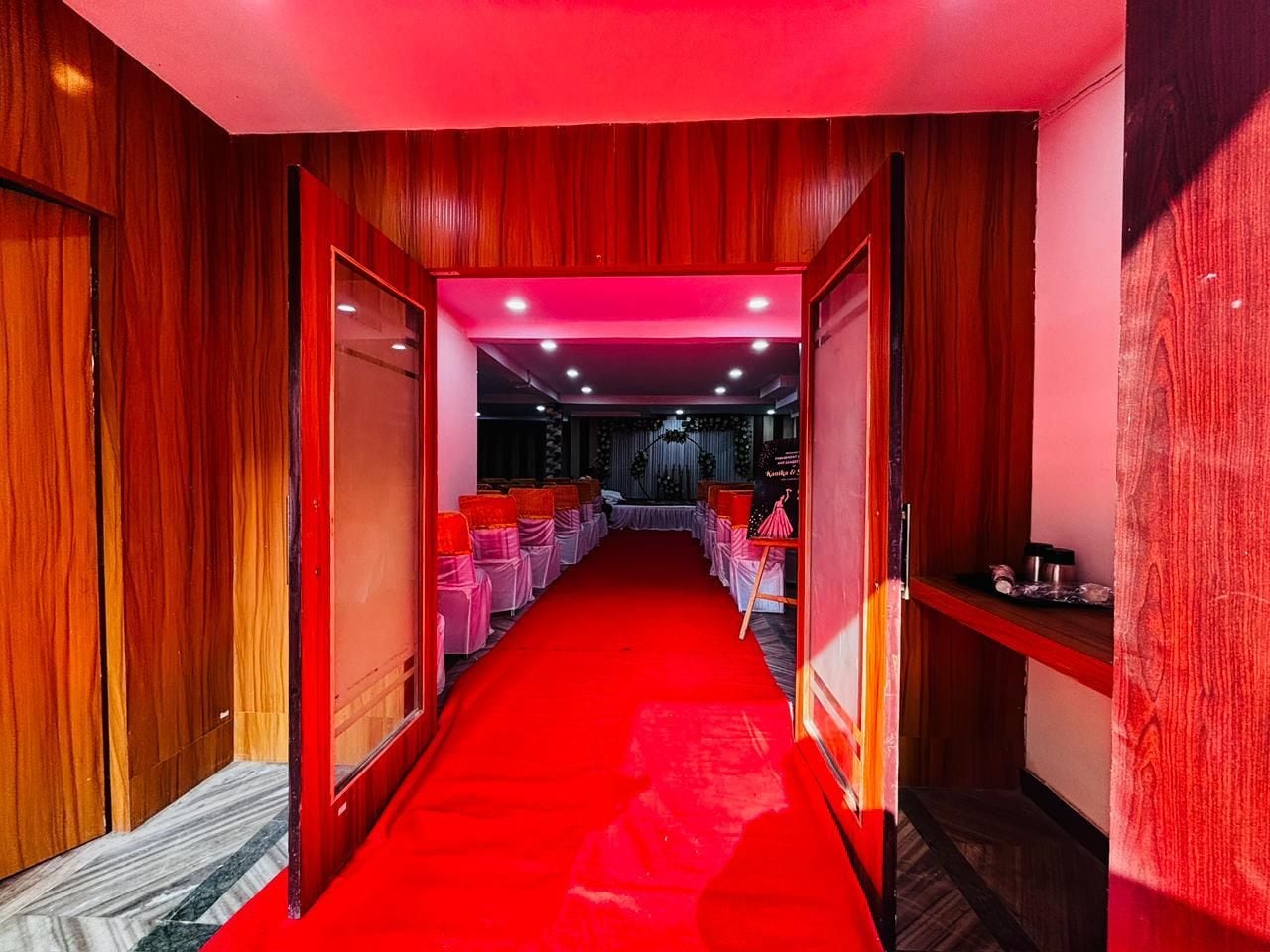 Un pasillo con alfombra roja que conduce a una habitación con techo y paredes rojas, y una puerta visible a la izquierda.
