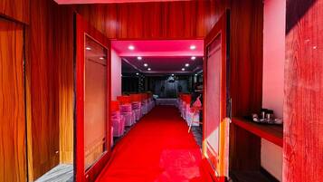 Un pasillo con alfombra roja que conduce a una habitación con techo y paredes rojas, y una puerta visible a la izquierda.