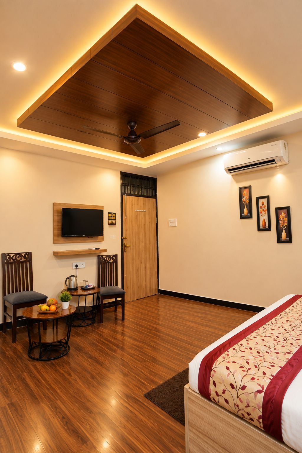 A hotel room with a wooden ceiling, a bed with a floral bedspread, a television, a desk with a plant, and a coffee maker.