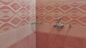 Une salle de bain avec des carreaux roses à motifs, une douche en verre et un robinet en métal.