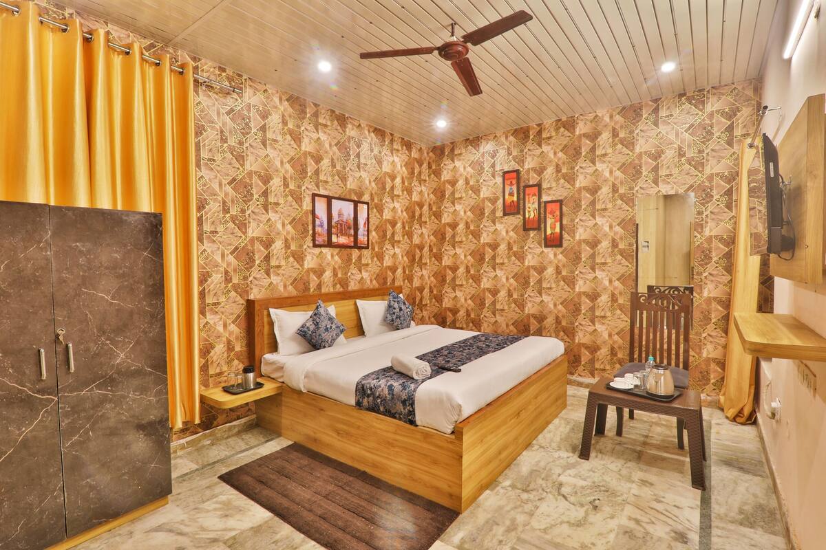 Un dormitorio con una cama de madera, una mesita de noche, una pequeña mesa con bandeja y un ventilador de techo.