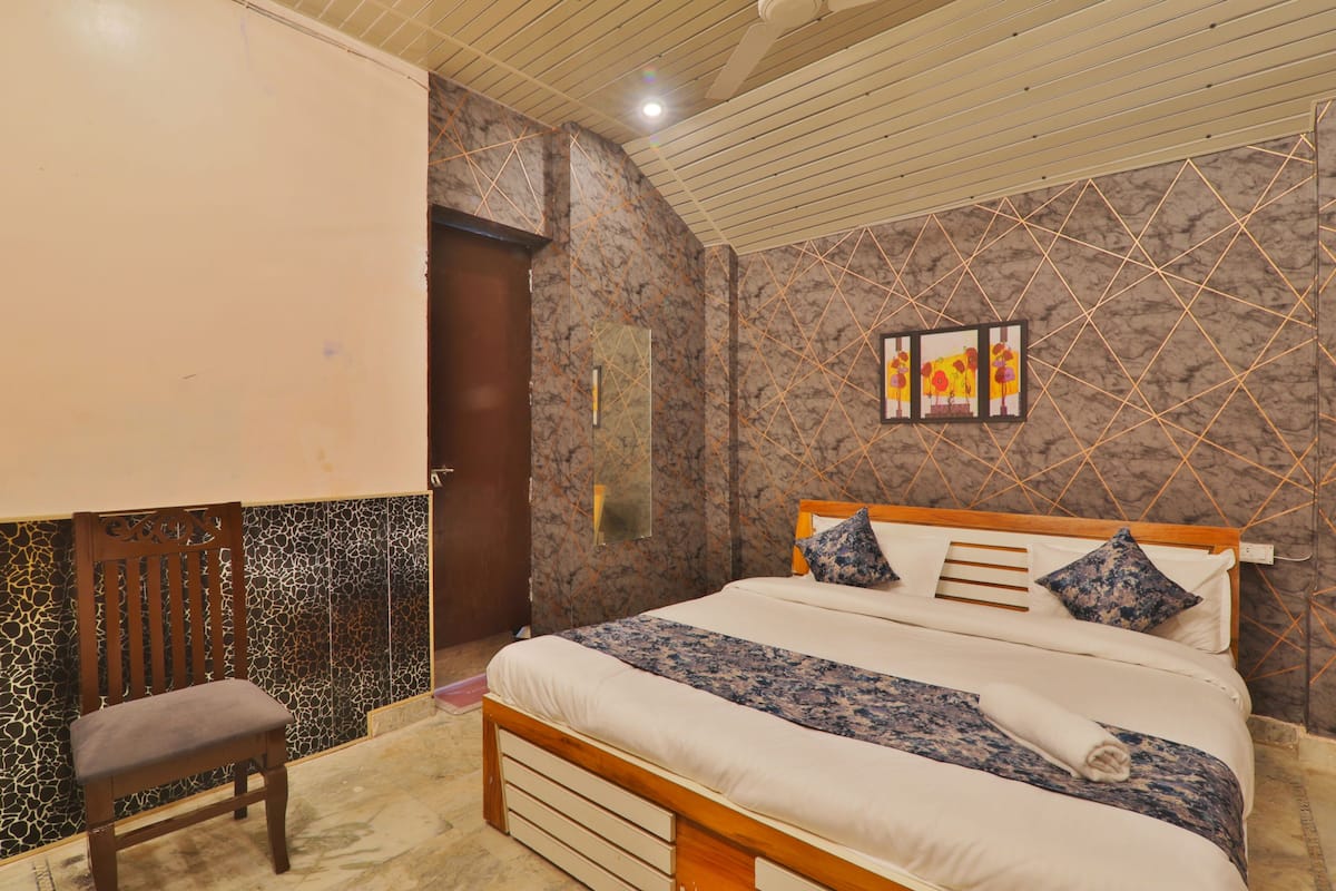 Un dormitorio con una cama, una silla, una obra de arte colgada en la pared y una puerta.