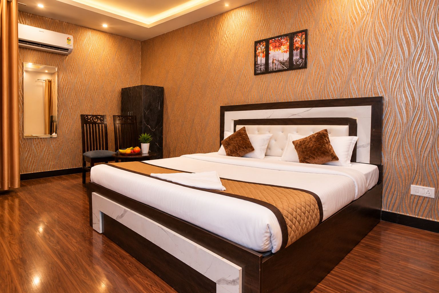 A hotel room with a large bed, a nightstand, a wardrobe, and a wall-mounted air conditioner.