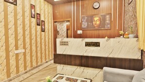 Un espace d’accueil doté d’un comptoir en marbre, de lambris en bois, d’une statue de Bouddha et d’une horloge.