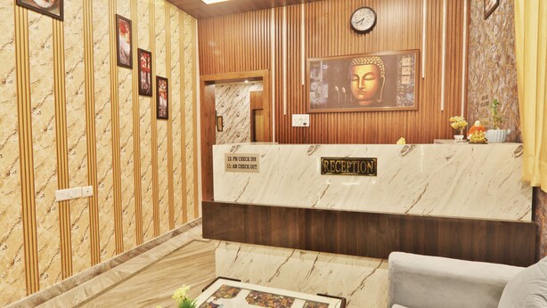 A reception area with a marble counter, wooden paneling, a Buddha statue, and a clock. - Hotel Kasol Heritage (Lucknow)