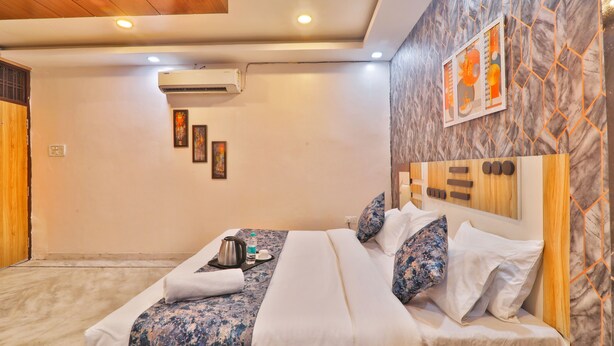 Une chambre d’hôtel avec un lit, une tête de lit en bois, un appareil de climatisation et un mur orné d’un motif géométrique.