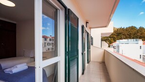 A balcony with a bed, a window, and green shutters. - GuestReady - Machico Apartment with Balcony (Machico)