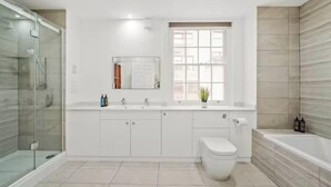 A modern bathroom with a glass shower enclosure, a white toilet, and a bathtub.