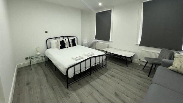 Une chambre à coucher moderne avec un lit, une table de chevet, une chaise et une grande fenêtre.