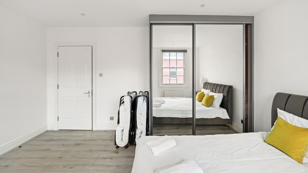 A modern hotel room with a large bed, a wardrobe, and a mirror.