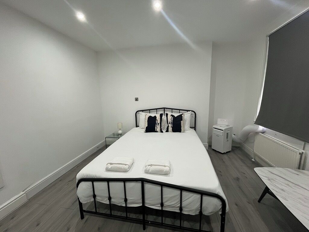 A bedroom with a single bed, a bedside table, a heater, and a radiator.