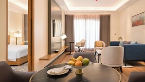 Una habitación de hotel con cama, una mesa de comedor con fruta, un sofá y un televisor.