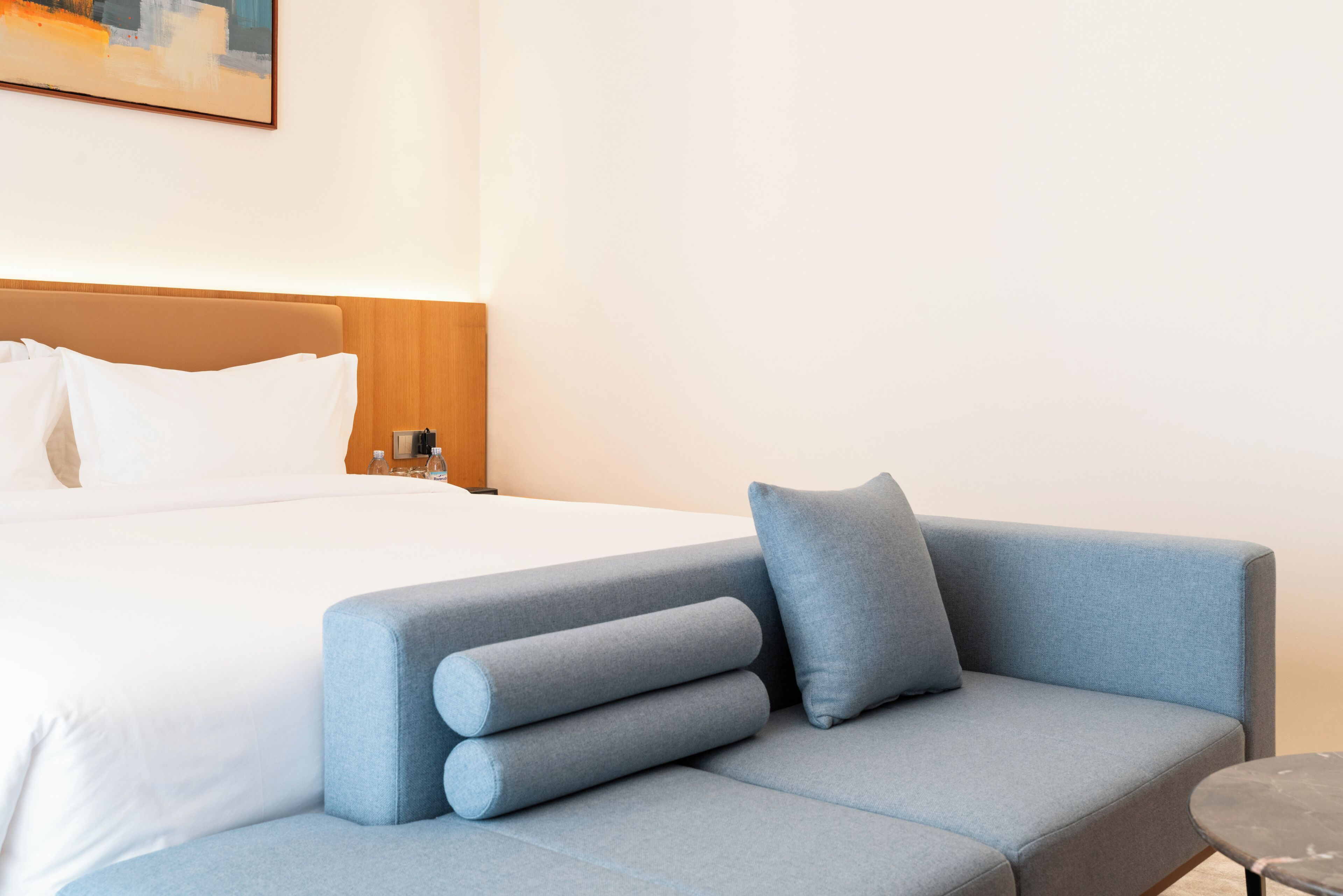 A hotel room with a bed, a blue sofa, and a small table.