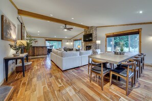 A spacious living area with a stone fireplace, a large sofa, and a dining table with chairs. - NW Family Oasis: 6BR Modern Gem Near Rainier! (Puyallup)