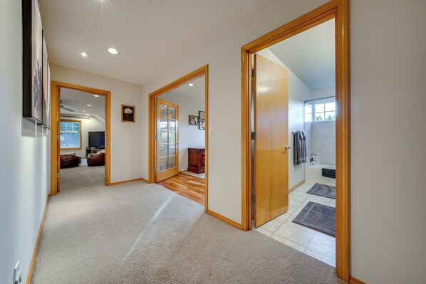 A hallway with wooden doors leading to a bathroom and a living area. - NW Family Oasis: 6BR Modern Gem Near Rainier! (Puyallup)