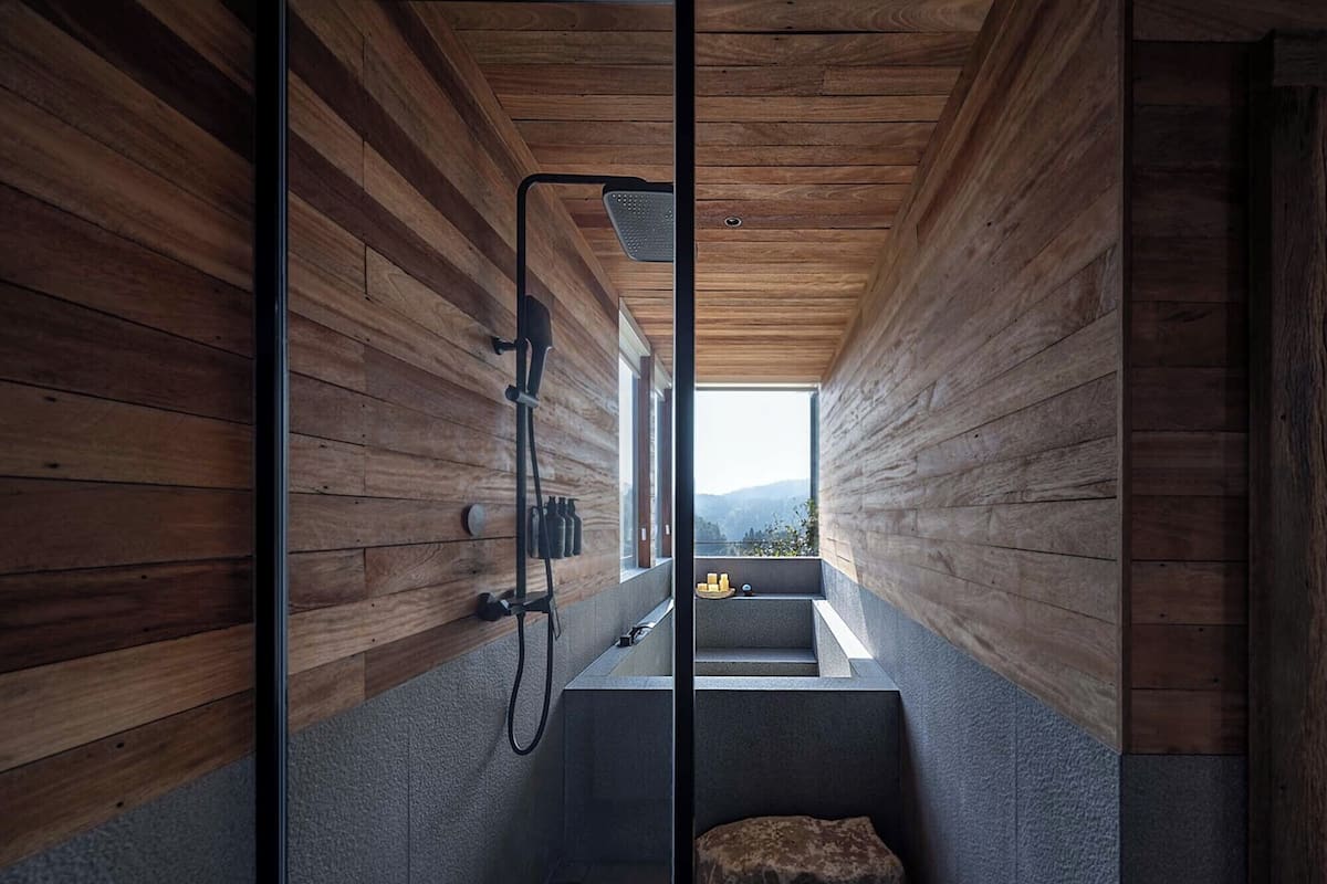 Un baño moderno con paredes de madera, cabina de ducha de cristal y vistas a montañas.