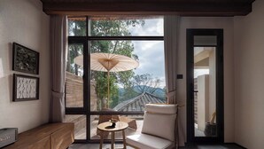A modern room with a large window, a wooden bench, a cushioned chair, and a small table with a bowl of fruit. - Shanyu Art Garden Homestay (Fuzhou)