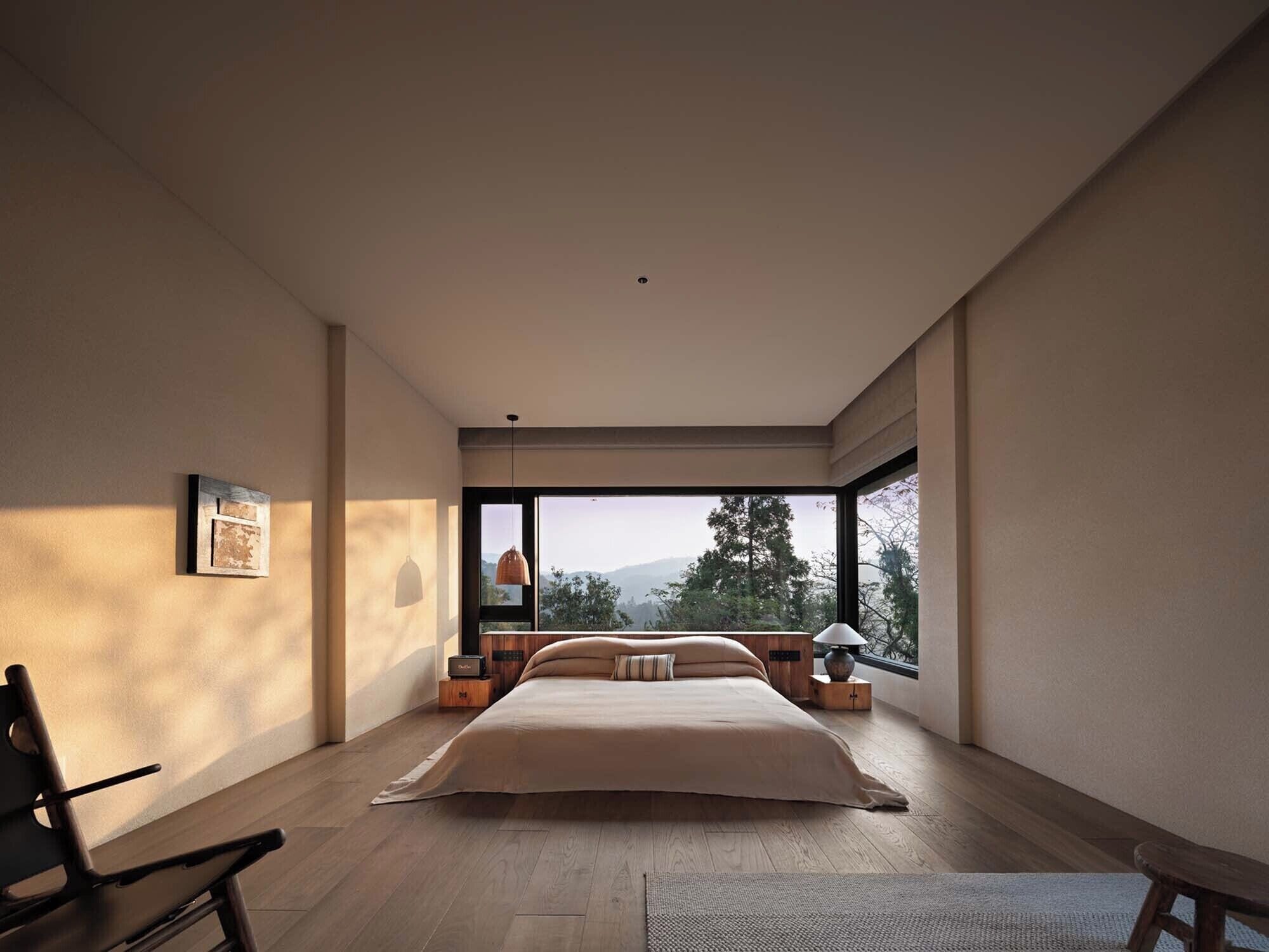 Ein geräumiges Schlafzimmer mit einem großen Bett, Blick ins Freie und einem modernen Design.