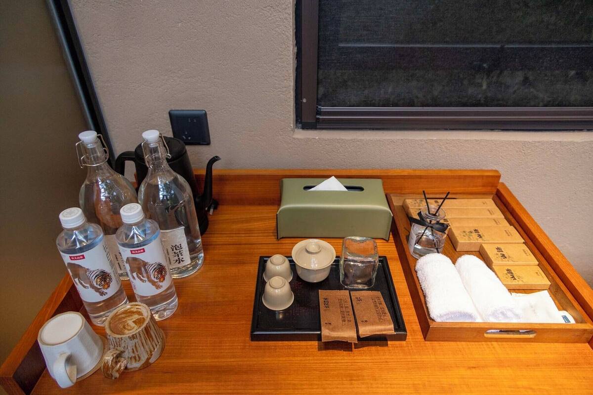 Una bandeja de madera con distintos artículos de aseo, como botellas, una caja de pañuelos y toallas.