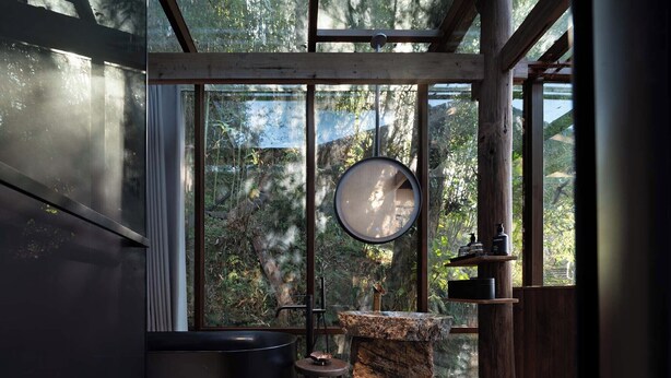 A modern bathroom with a large bathtub, a round mirror, and a wooden shelf with toiletries. - Shanyu Art Garden Homestay (Fuzhou)