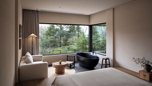 A modern bedroom with a large window, a bed, a sofa, a round wooden table, and a black bowl-shaped chair. - Shanyu Art Garden Homestay (Fuzhou)