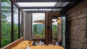 A room with a bed, a balcony with wicker furniture, and a stone wall. - Shanyu Art Garden Homestay (Fuzhou)