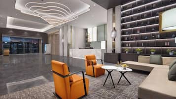 A modern lobby with a reception desk, seating area, and a bookshelf.