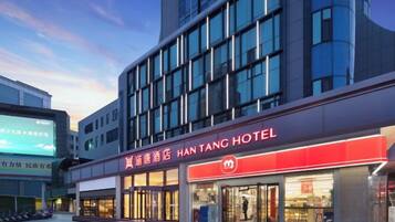 A hotel with a modern facade, large windows, and a prominent red sign.